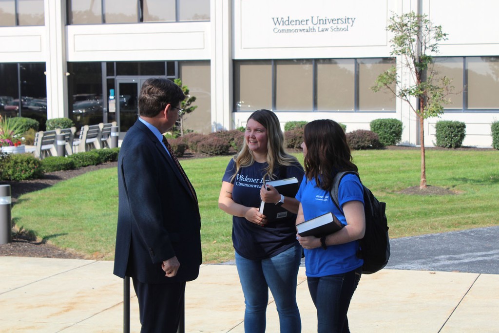 Two WLC student ambassadors talking to Professor Johnson in front of the Library/Classroom Building.
